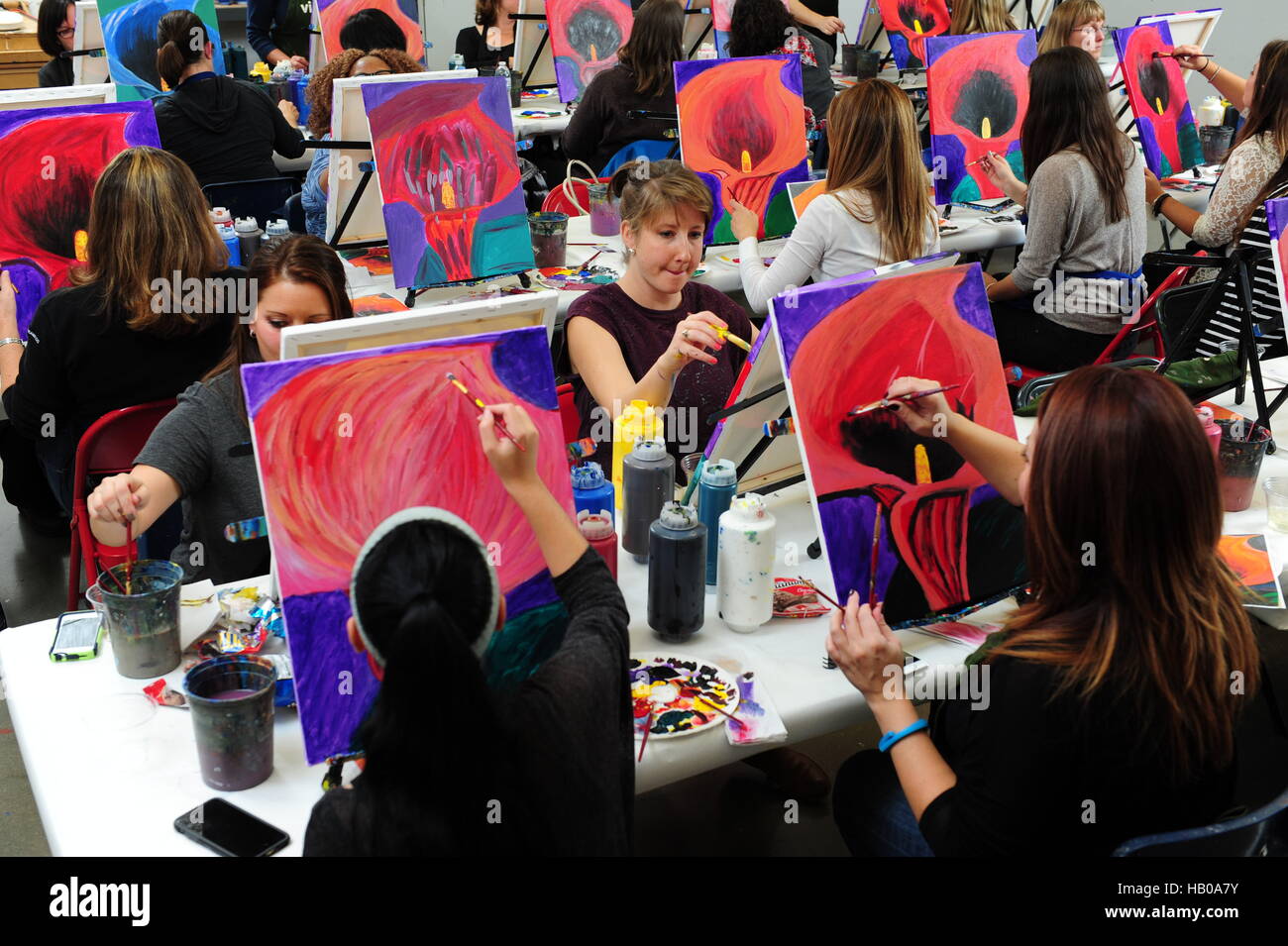Adult education art class people learning to paint flowers in an evening classroom Stock Photo