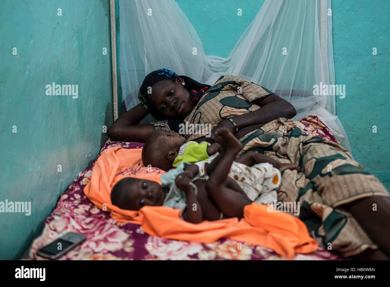 DIOILA - MALI:  A woman lays with her two kids suffering malnutrition ath the Intensive Nutritional Unit of the Dioila hospital on November 7 2016 in  Stock Photo