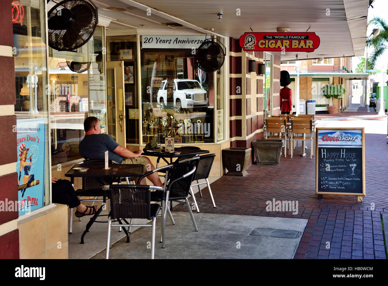 Table and chairs with customer at sidewalk cafe bar “Cigar Bar” in downtown Fort Myers, Florida