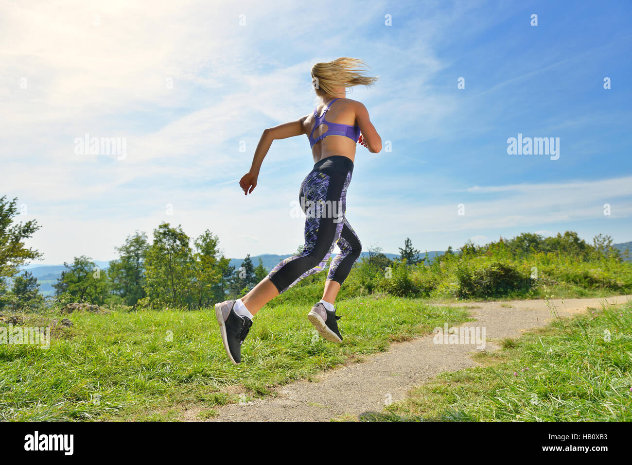 Young girl runner jogging on a mountain trail in the beautiful
