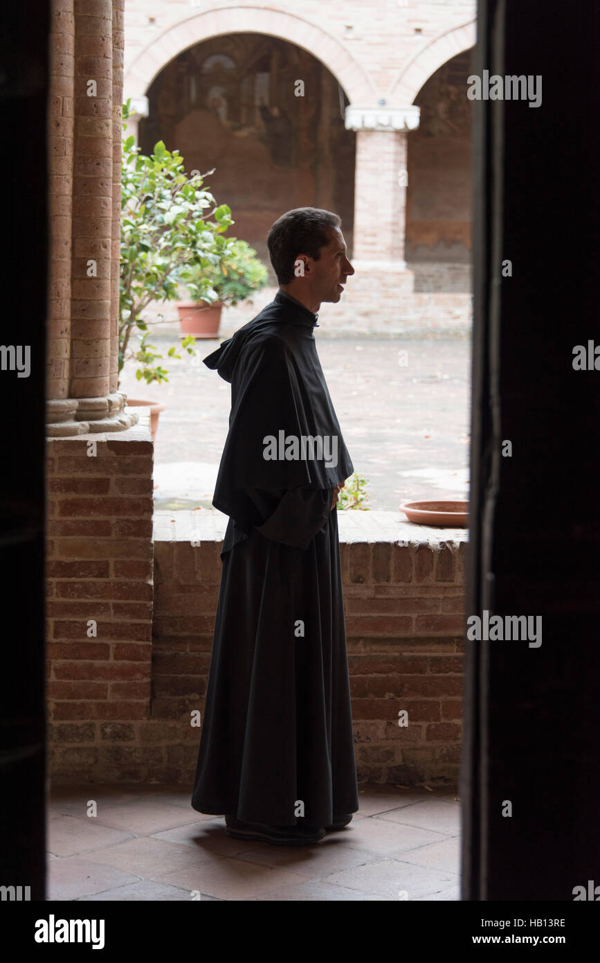 A catholic priest in the cloisters of St Nicholas's church Stock Photo