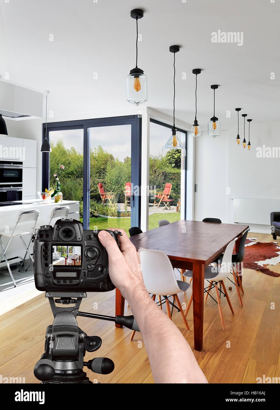 Hands holding a professional camera on tripod taking picture in luxury living room Stock Photo
