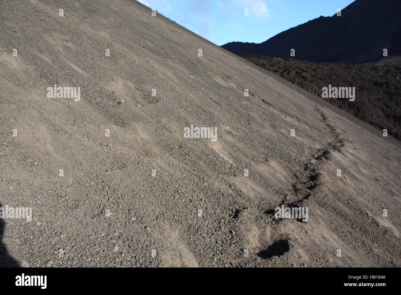 footsteps crossing ash slope. Background: Lava fields. Volcano Pacaya, Guatemala Stock Photo