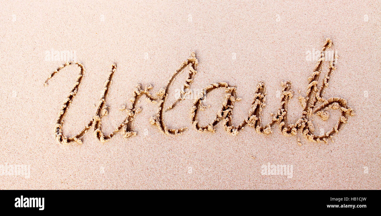 Word  Urlaub written in sand. Stock Photo