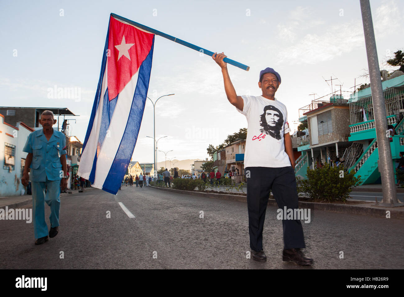 Santiago De Cuba, Cuba. 04th Dec, 2016.  A man (right) wearing a Che Guevara t-shirt is carrying a Cuban flag while walking towards Santa Ifigenia's cemetery where Fidel Castro's ashes are being buried. Castro's ashes have been crossing Cuba from Havana throughout 4 days and being paid tribute by hundreds of thousand of Cubans - Castro passed on Friday, Nov 25th. Photo: Alessandro Vecchi/dpa/Alamy Live News Stock Photo