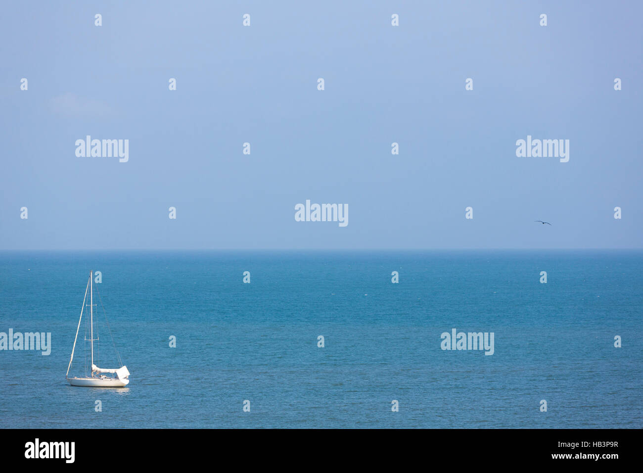 Sailboat with no sail sailing on flat blue water in Venezuela Stock Photo