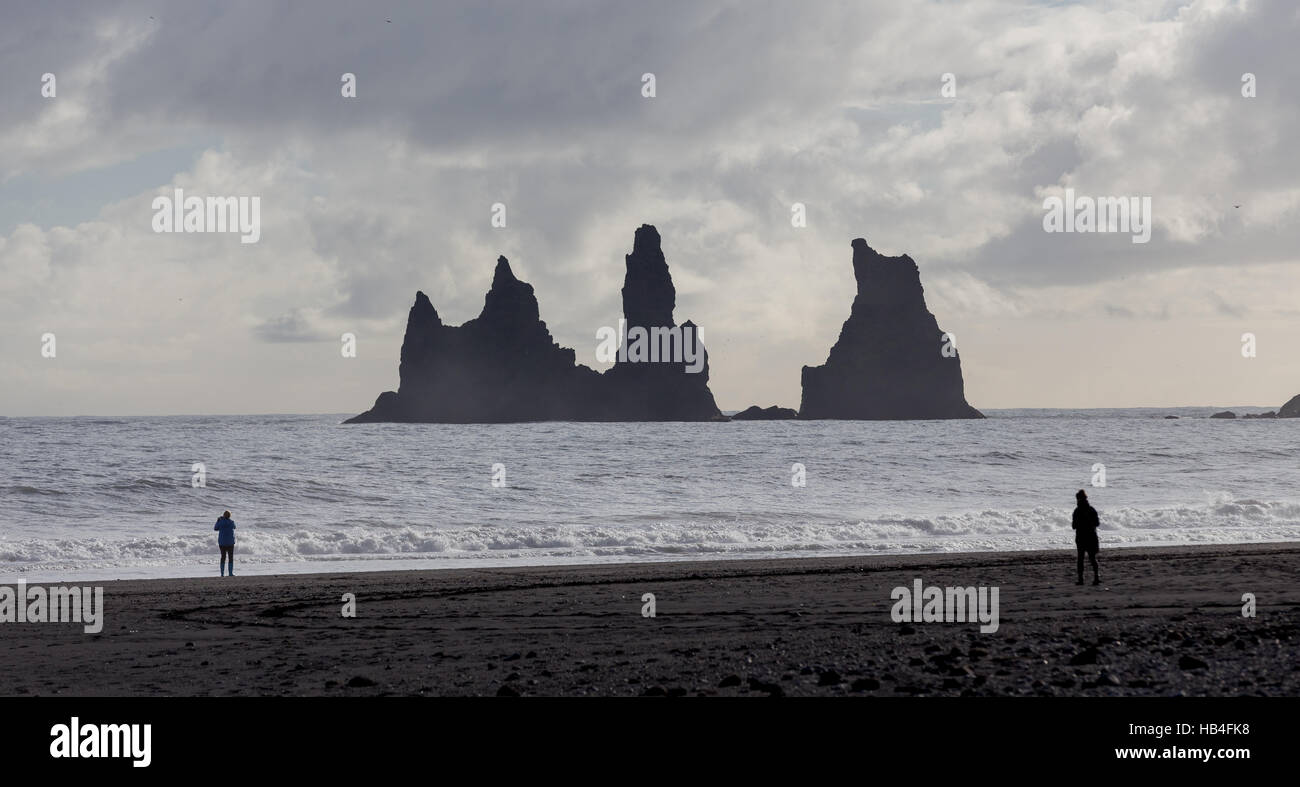 Two people on a beach looking at rock formations in Vik Iceland Stock Photo