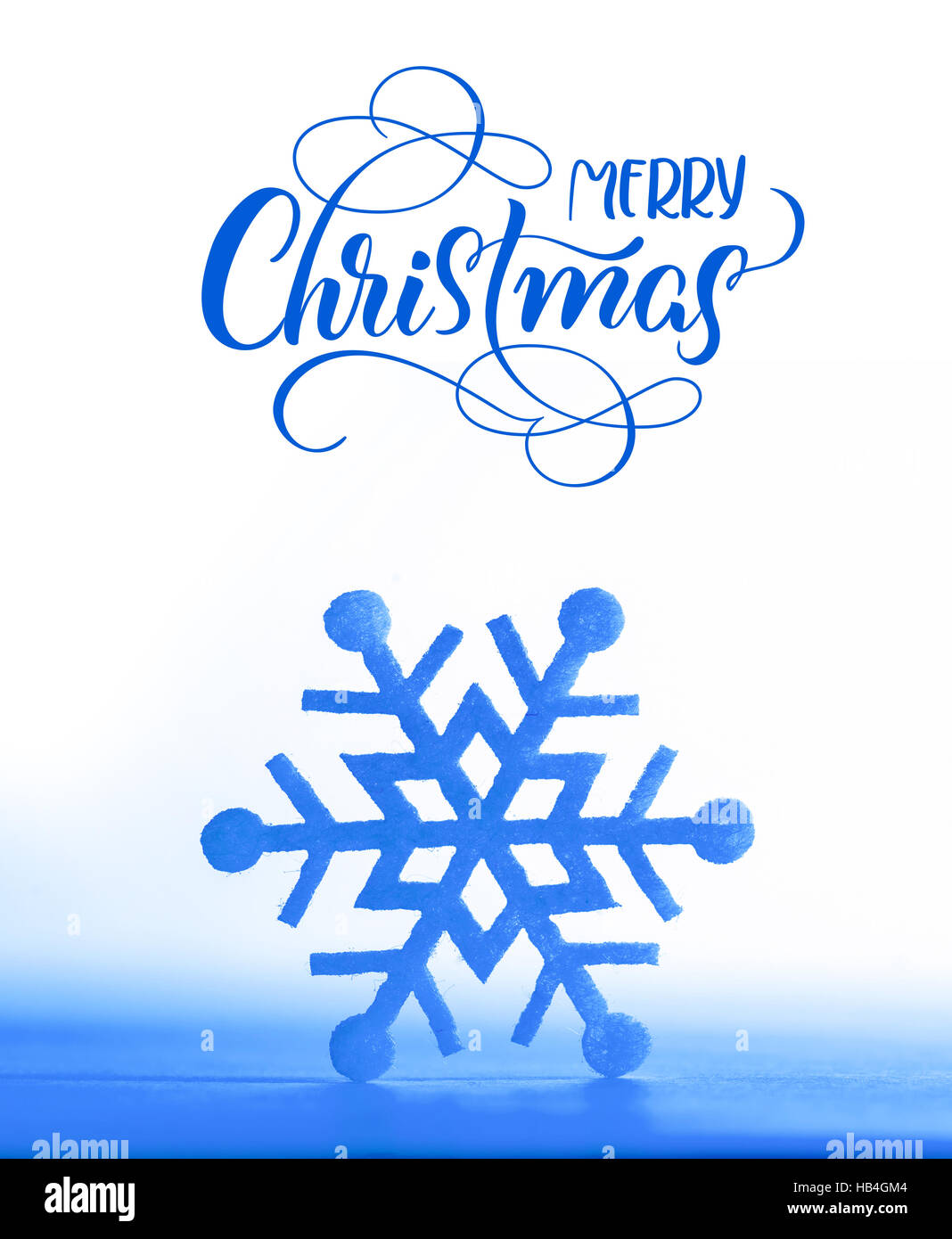 decoration. Beautiful snowflake on real snow outdoors with text Merry Christmas. Lettering calligraphy Stock Photo