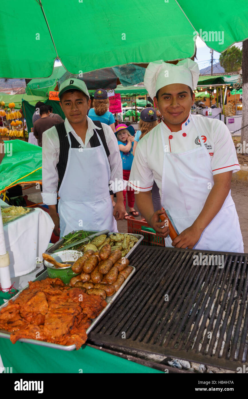 Two male cooks at barbecue grill smiling towards the camera farmers market Antigua Guatemala Stock Photo