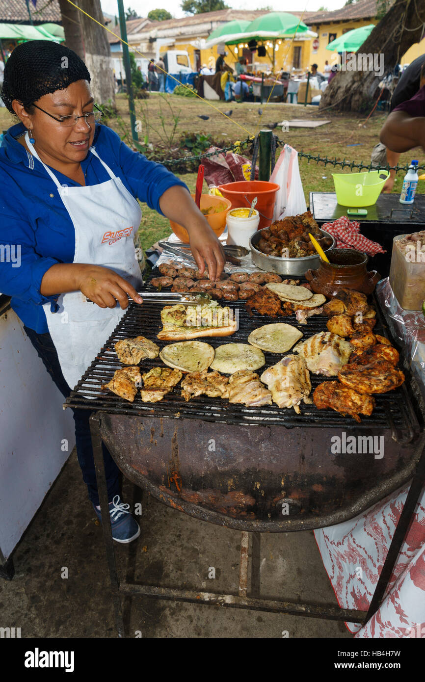 Female cook tending to barbecue grill farmers market Antigua Guatemala Stock Photo