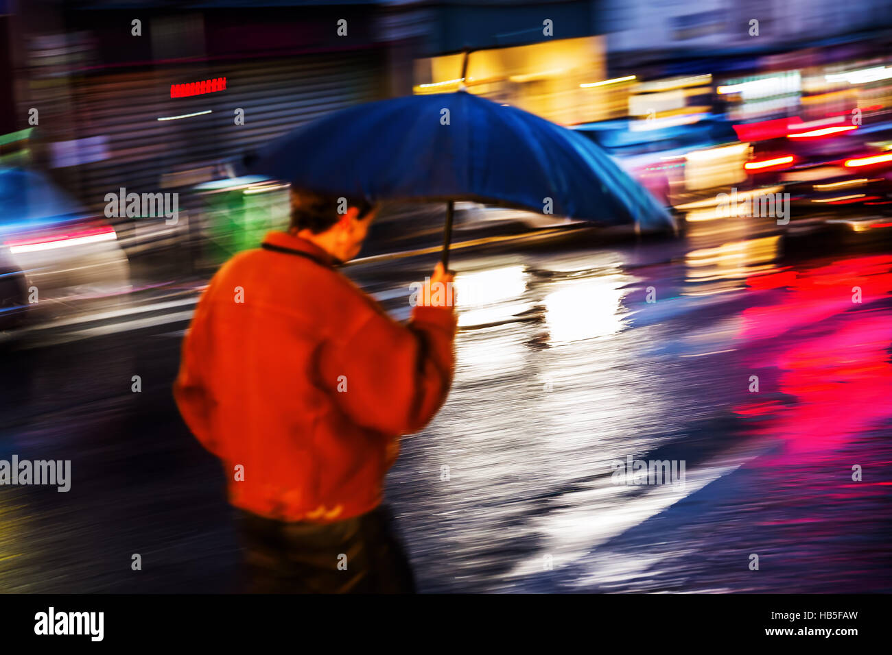 picture with motion blur of a man with umbrella walking at night in the ...