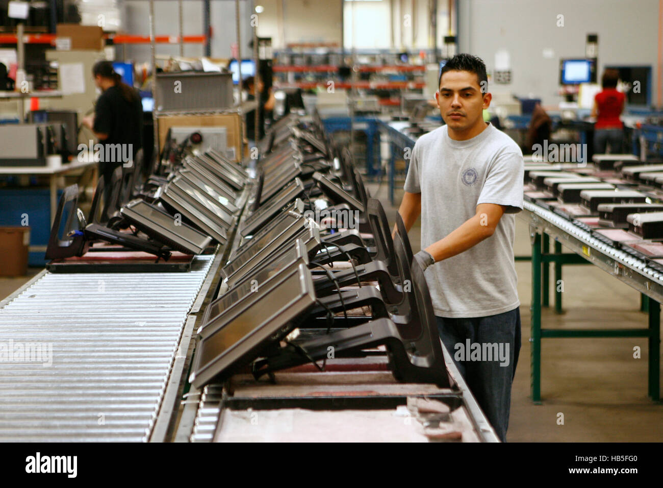 A Worker Pushes Flat Screen Computer Monitors Down The Line For 