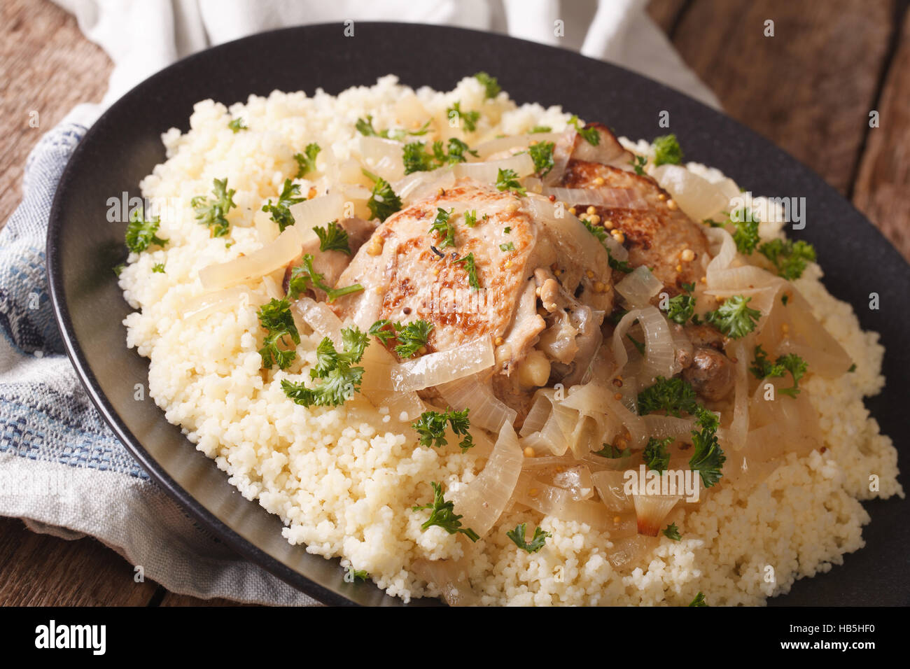 Yassa chicken stewed with marinated onions and couscous close up on a