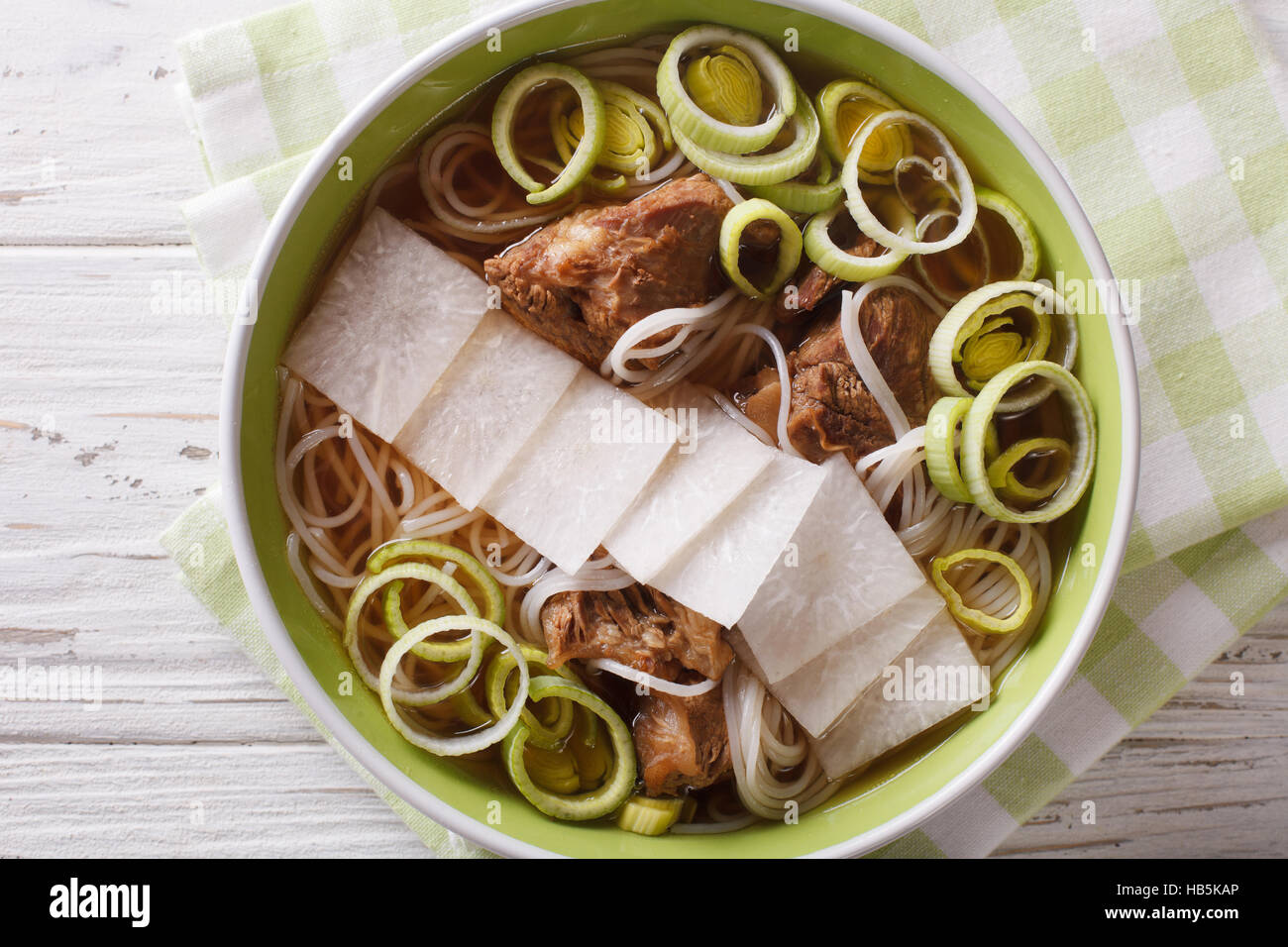 Korean beef ribs soup, rice noodles, leeks and daikon close up in a