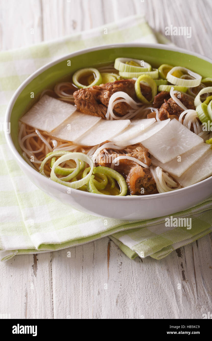 Korean beef ribs soup, rice noodles, leeks and daikon close up in a