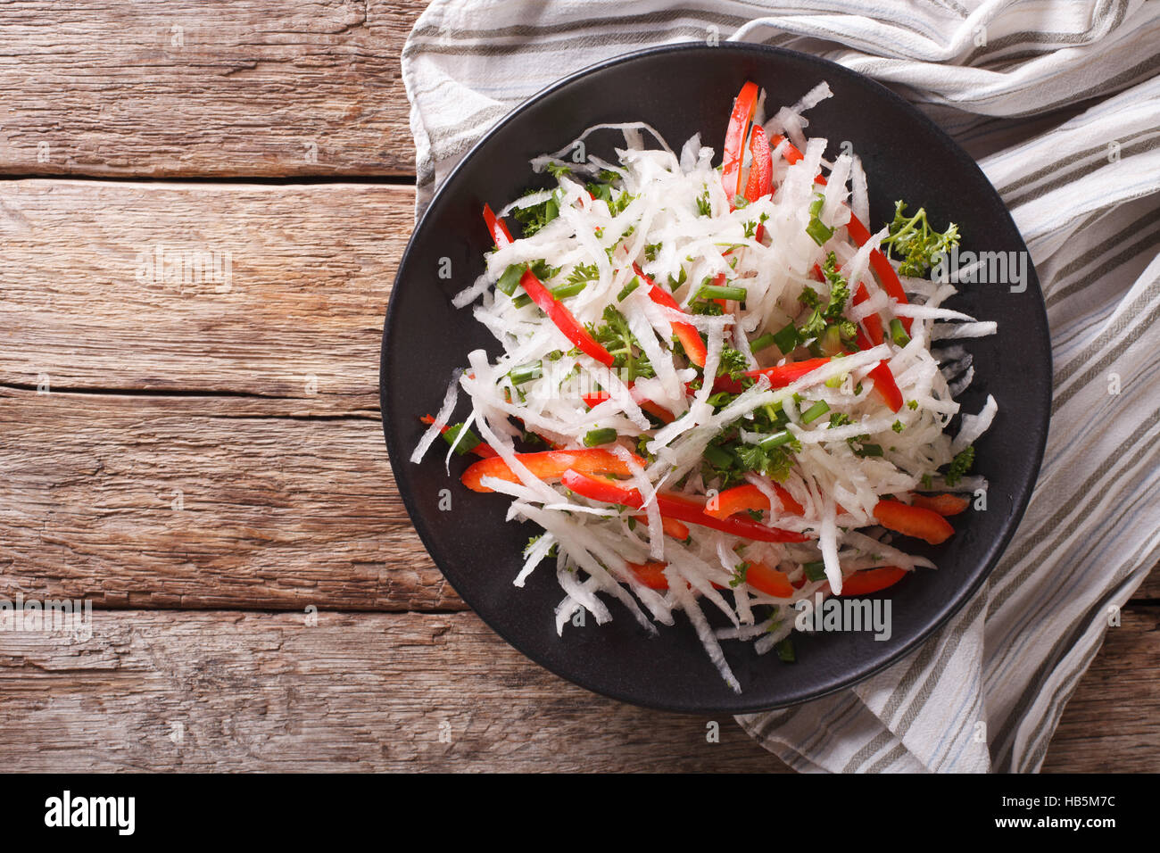 Fresh salad of daikon with pepper and herbs closeup on a plate. horizontal view from above Stock Photo