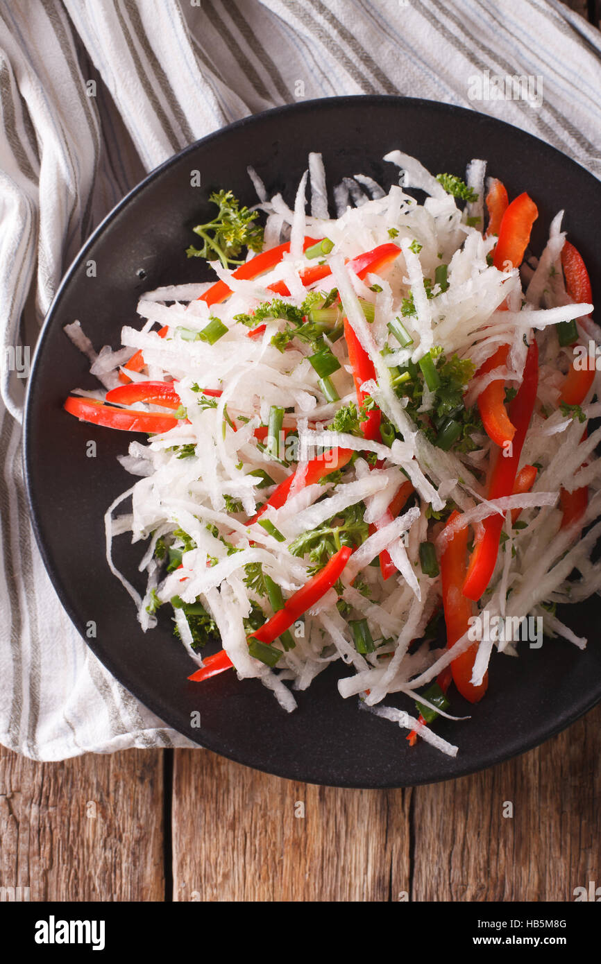 healthy food: salad of daikon with pepper and herbs closeup on a plate. vertical view from above Stock Photo