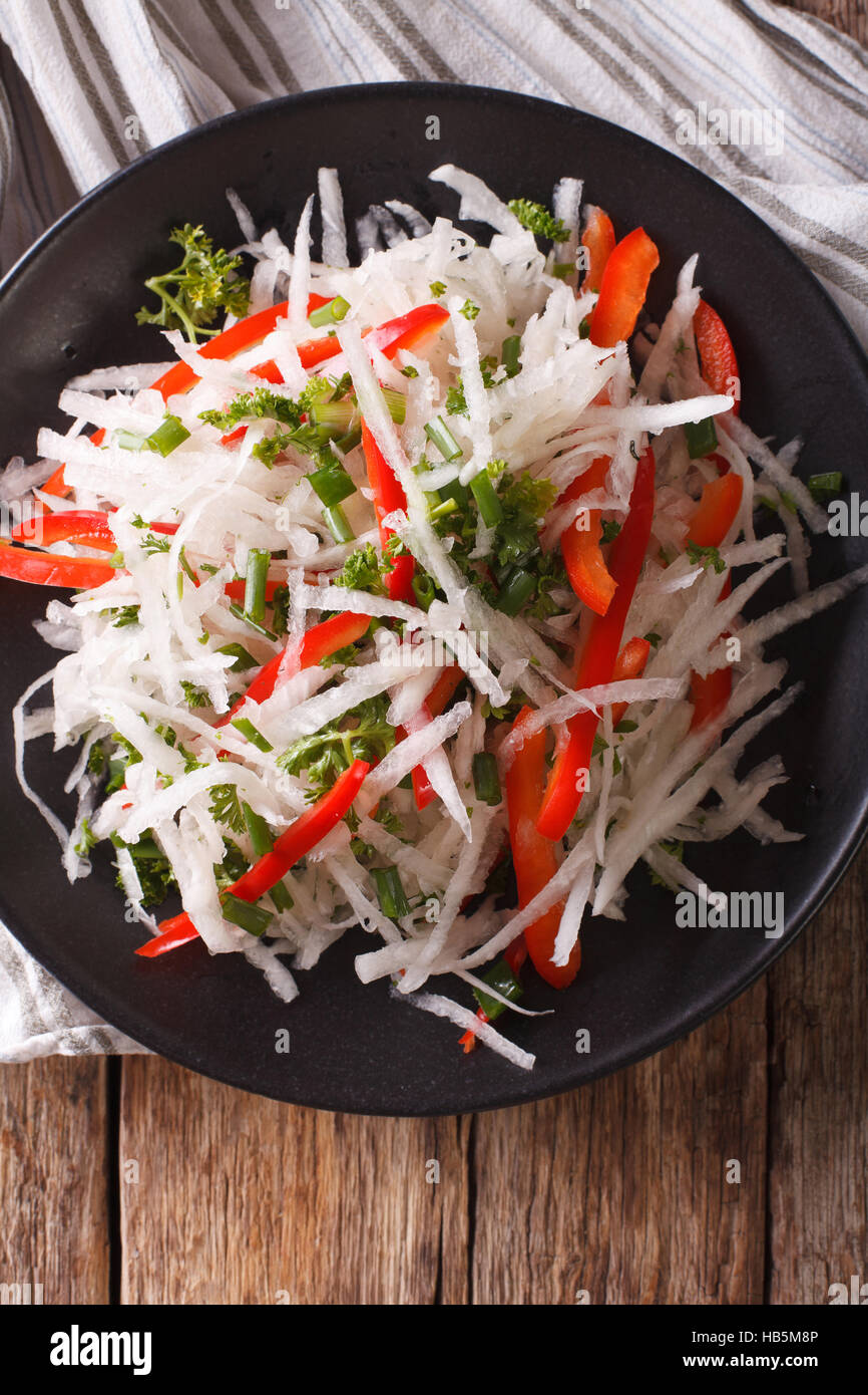 Tasty salad of daikon with pepper and herbs closeup on a plate. vertical view from above Stock Photo