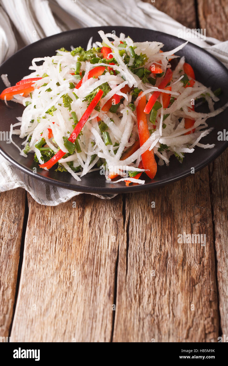healthy food: salad of daikon with pepper and herbs closeup on a plate. vertical Stock Photo