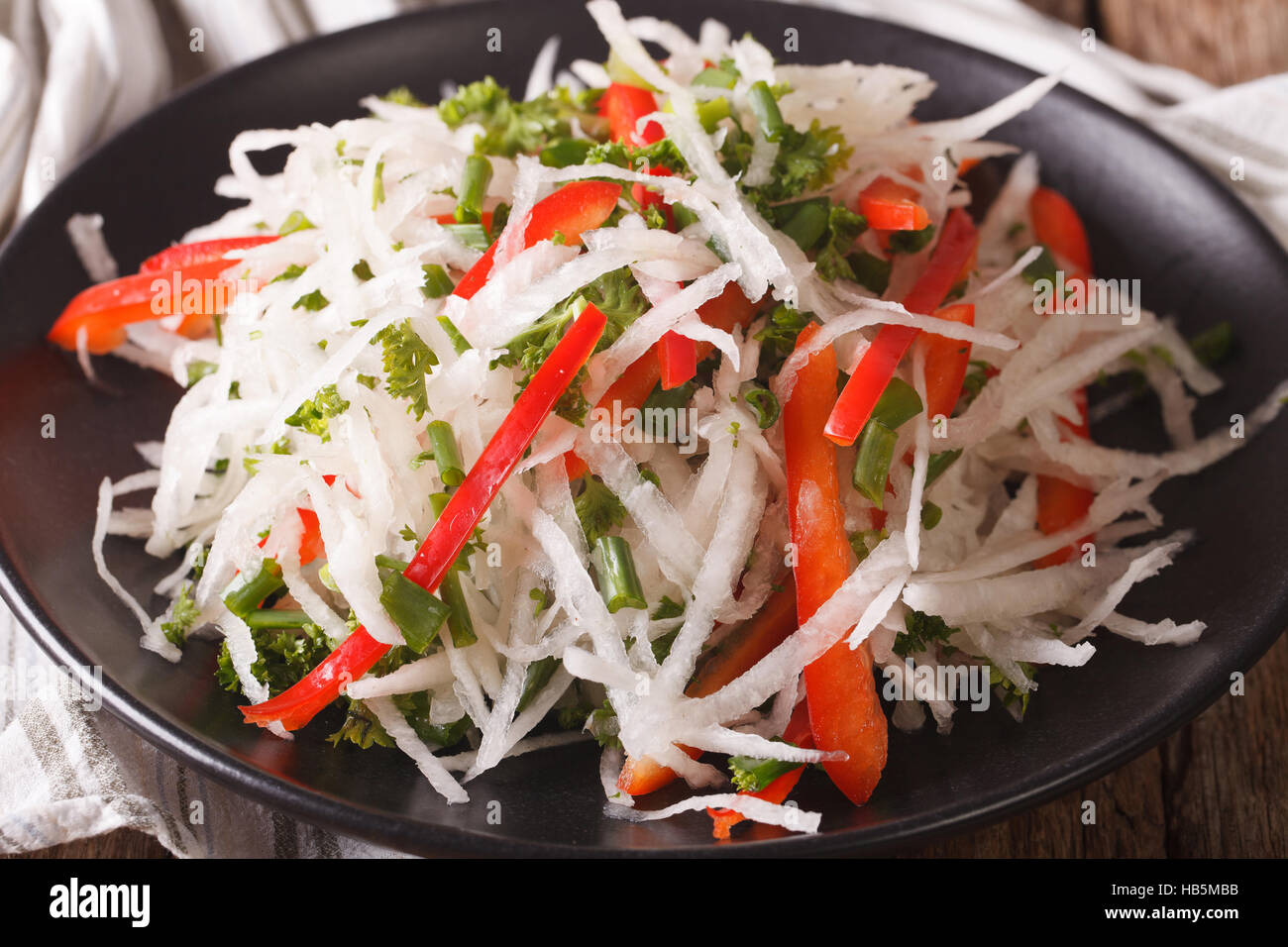 Fresh salad of daikon with pepper and herbs closeup on a plate. horizontal Stock Photo