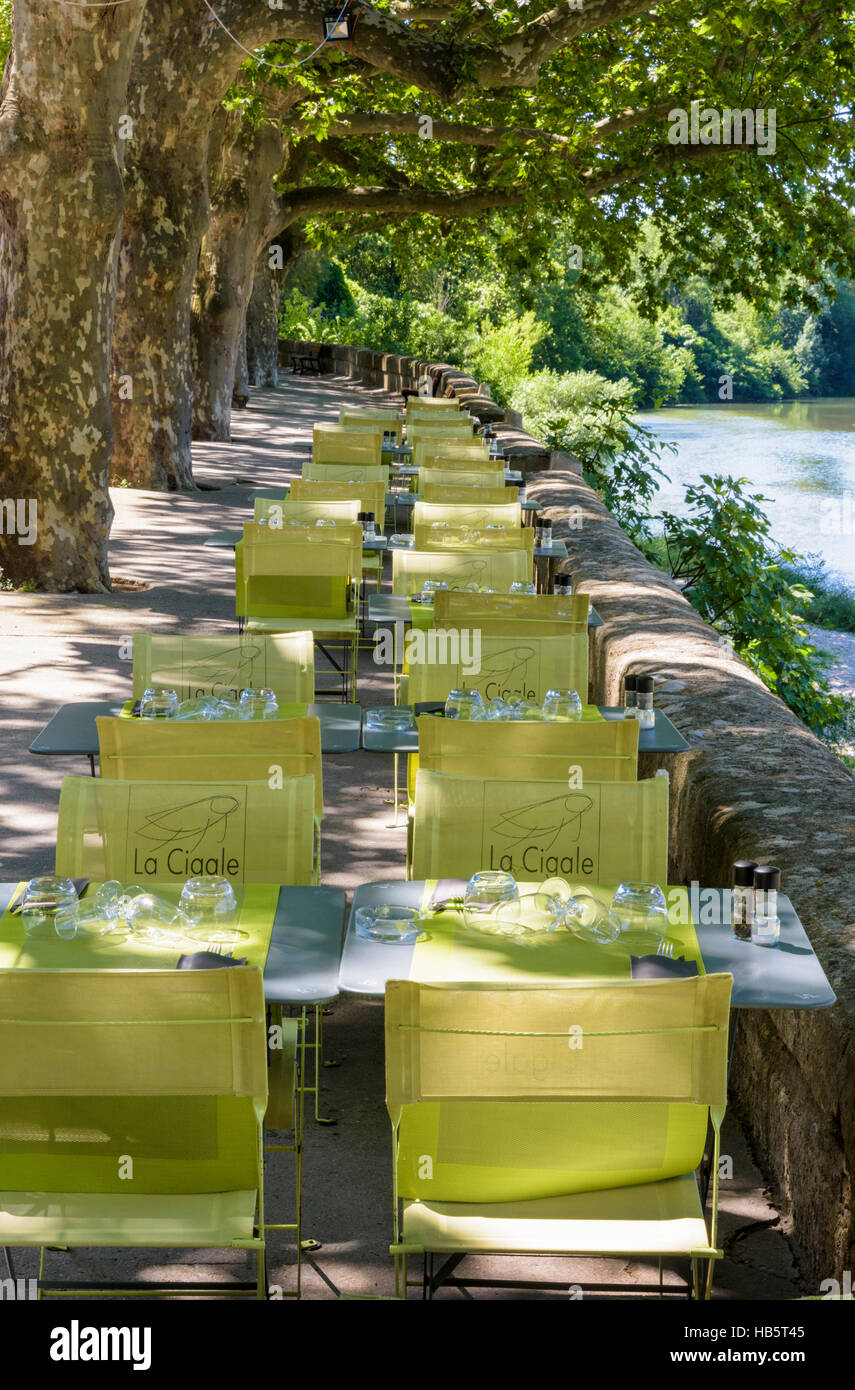 Shaded restaurant tables and chairs along the banks of the Vidourle River, Sommières, Gard, France Stock Photo