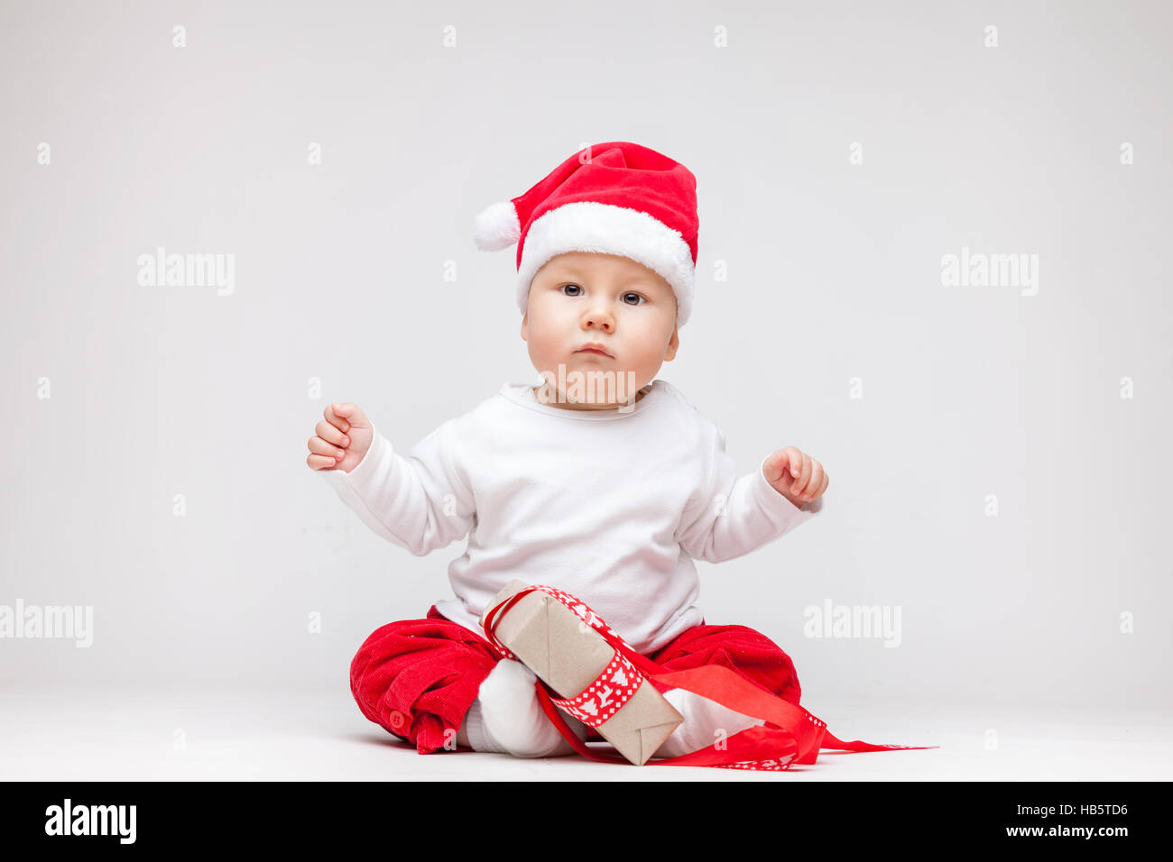 Adorable young baby boy wearing a Santa hat opening Christmas presents Stock Photo