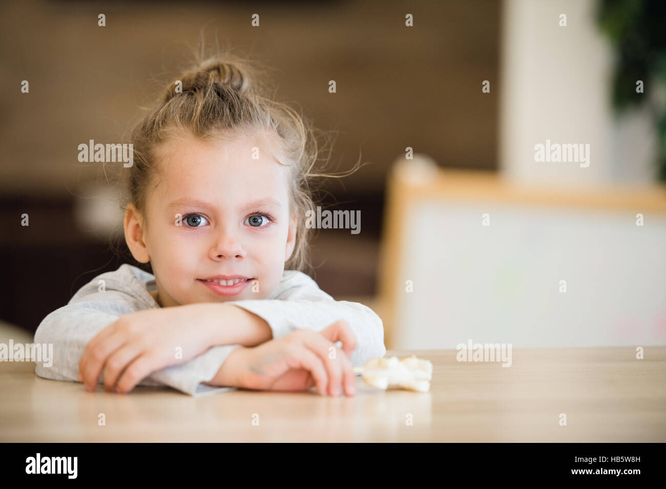 Beautiful calm little girl sitting at wooden table Stock Photo - Alamy