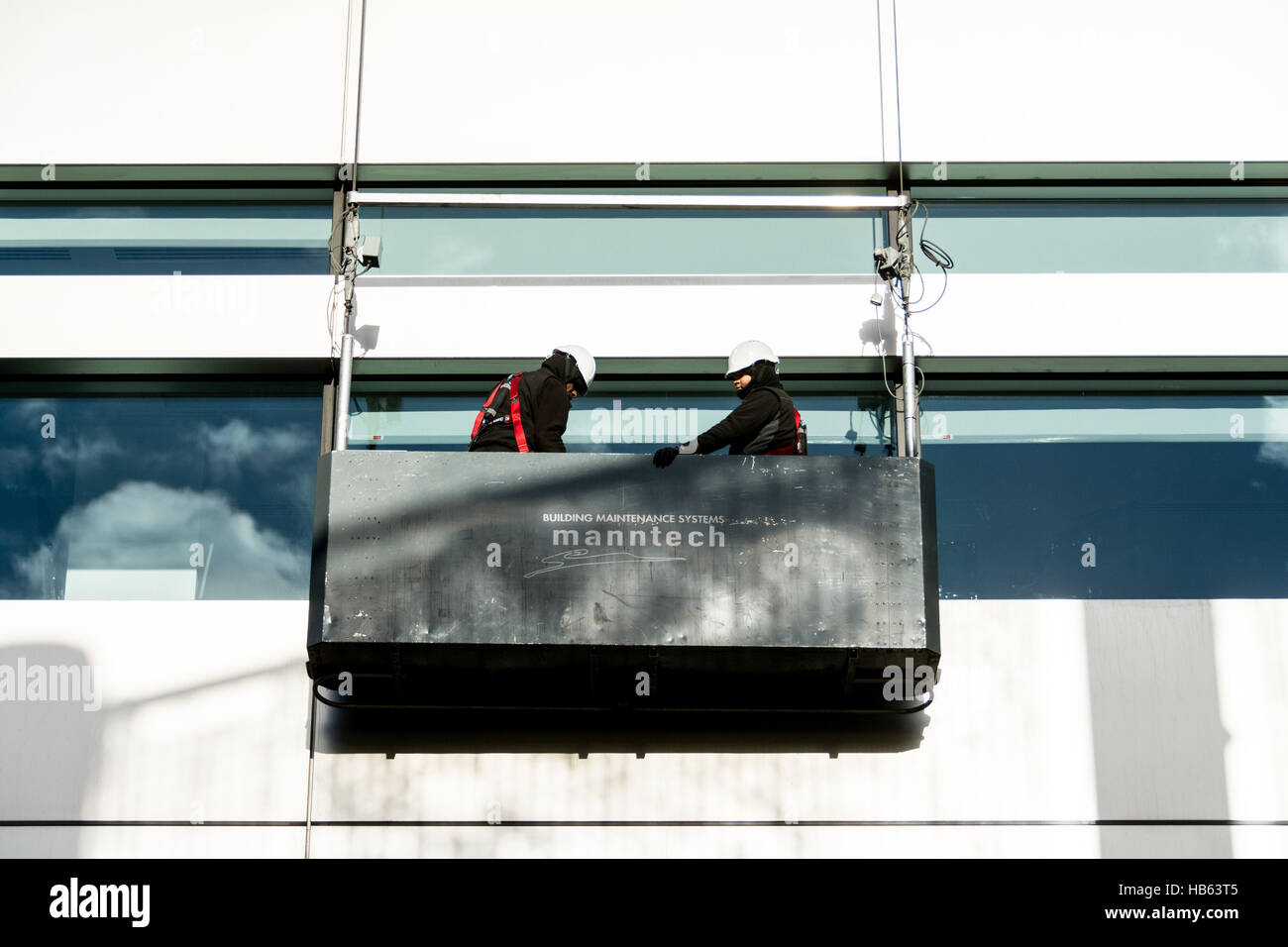 Window cleaners in a gondola outside the Headquarters of UBS at Broadgate Circle, Broadgate, City of London, England, U.K. Stock Photo