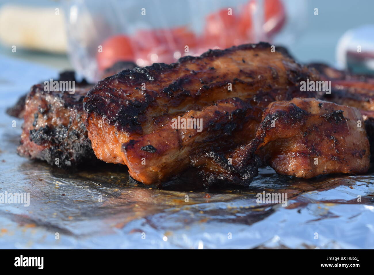 Strips of barbecue meat on tin foil on blurred background Stock Photo