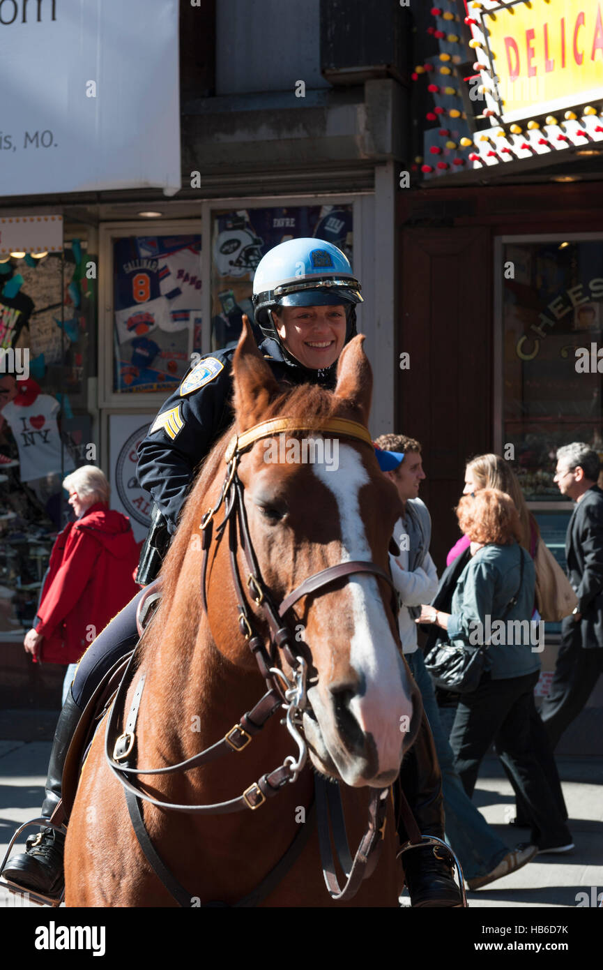 A horseback female NYPD officer smiling at the camera at Times Square, New York City Stock Photo
