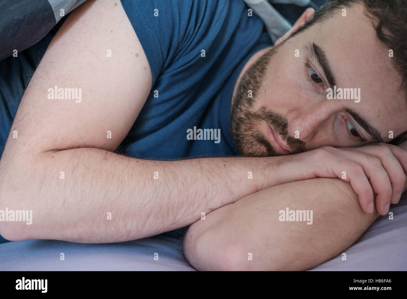 Depressed man lying in his bed feeling bad Stock Photo