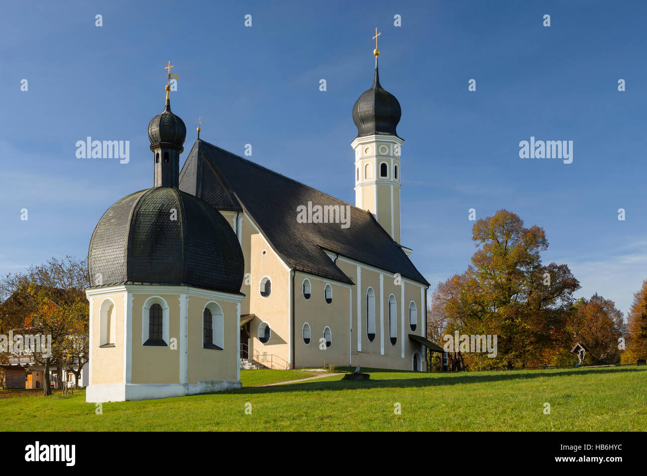 Colourful facade, steeples and roof of the baroque Wilparting pilgrimage church and chapel against the blue sky in the morning sun, Bavaria, Germany Stock Photo