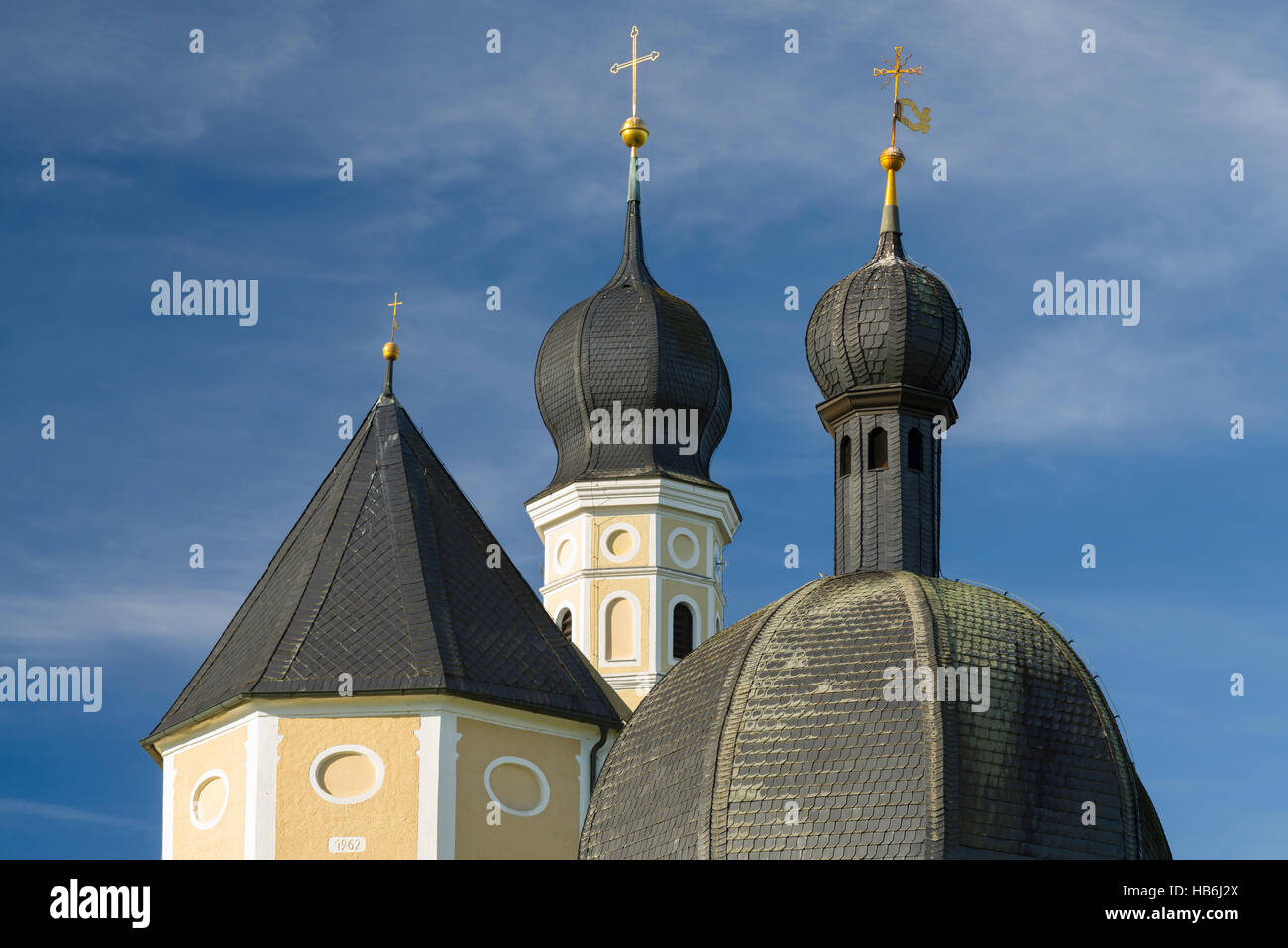 Colourful facade, steeples and roof of the baroque Wilparting pilgrimage church and chapel against the blue sky in the morning sun, Bavaria, Germany Stock Photo