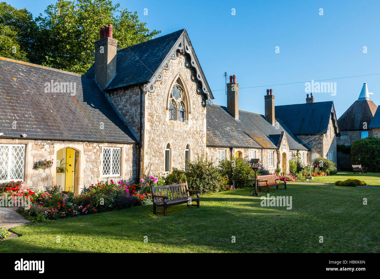 England, Sandwich. St Thomas's hospital, now almshouses. View along 1850's building with green lawn in foreground. Bright sunshine, clear blue sky. Stock Photo