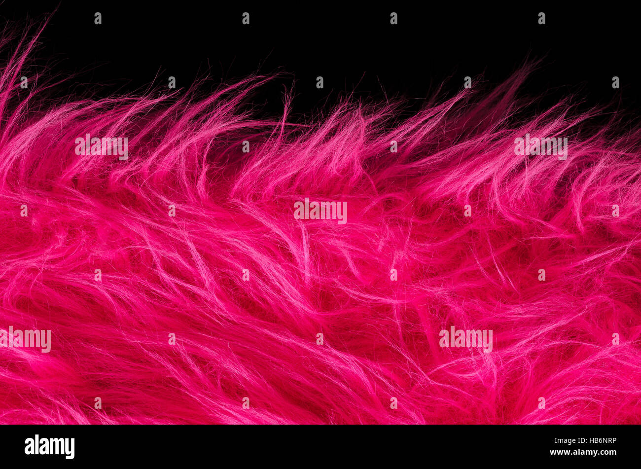 Pink plush fabric on black background horizontal. Very soft polyester textile made of synthetic fibers with long hairs. Macro. Stock Photo