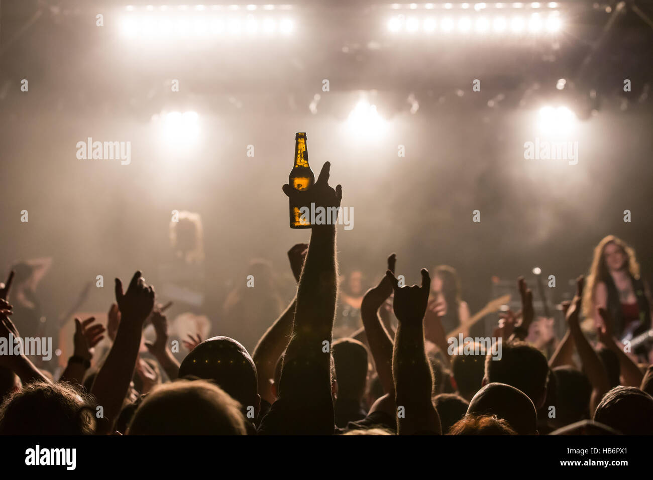 Concertgoers holding beer bottle in the air Stock Photo
