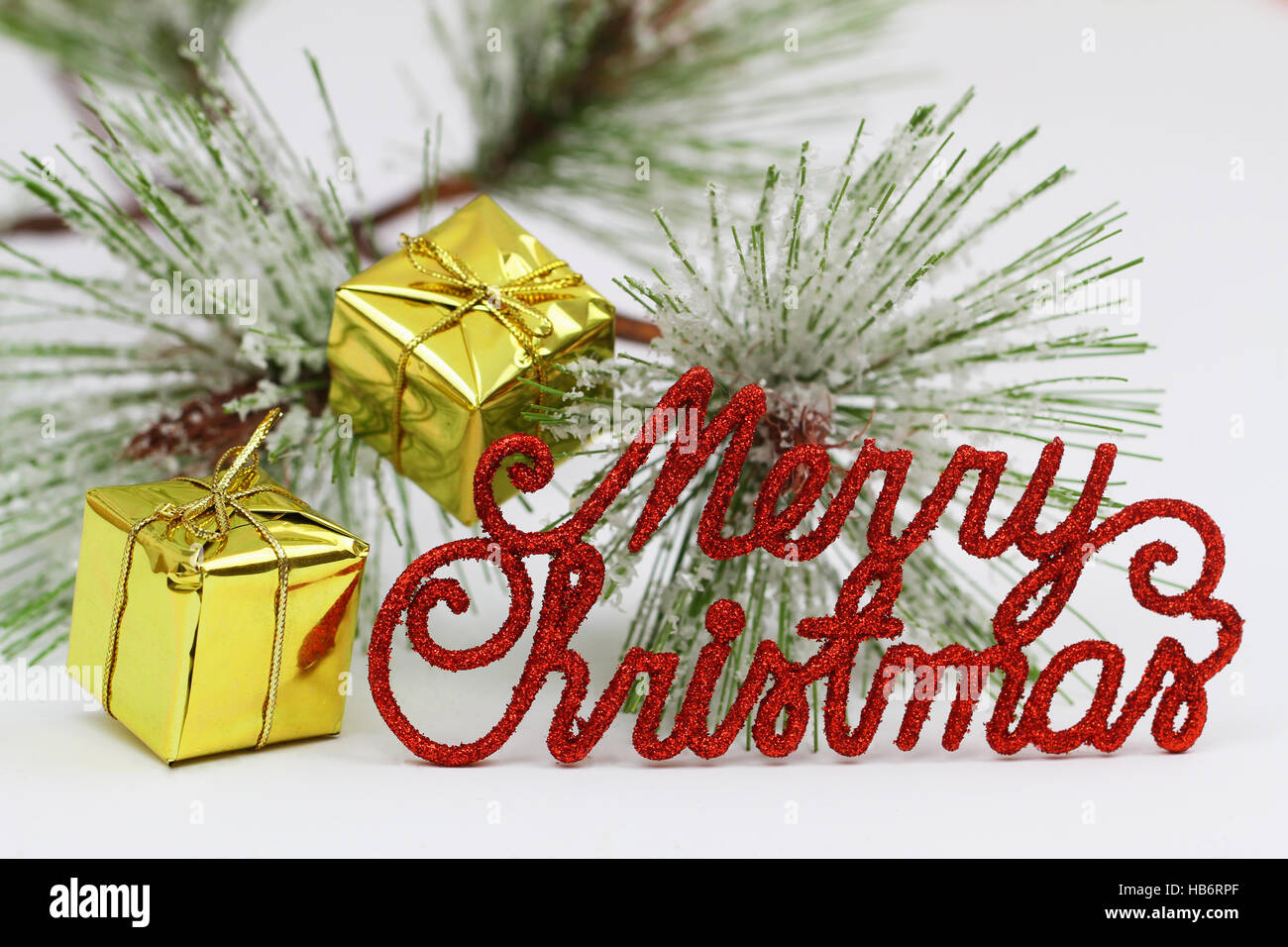 Merry Christmas written with shiny red letters, presents and pine Stock Photo