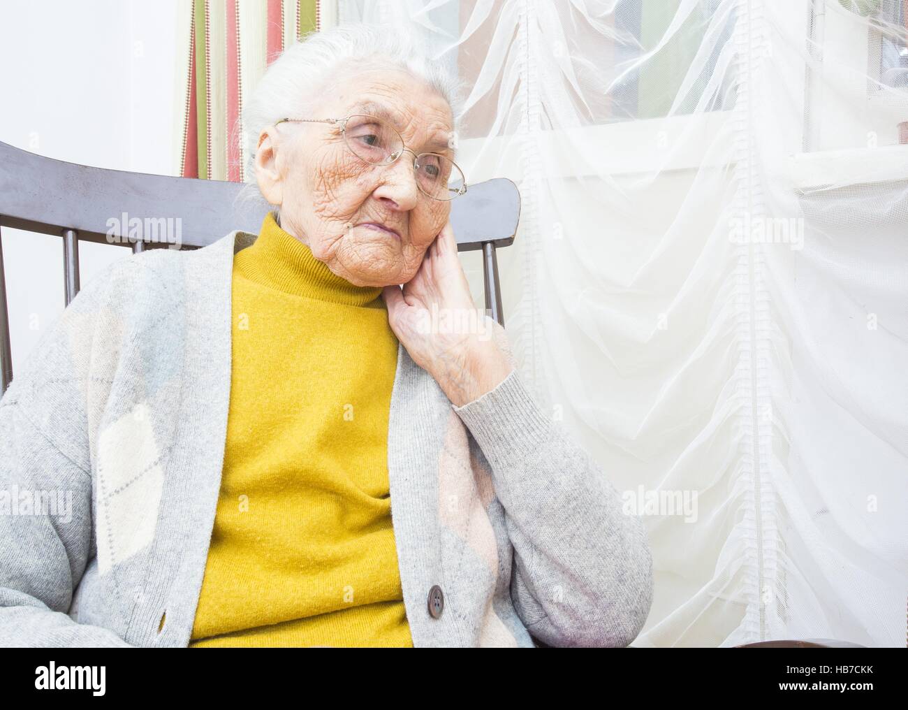Sad elderly lady sitting in a chair and thinking Stock Photo - Alamy