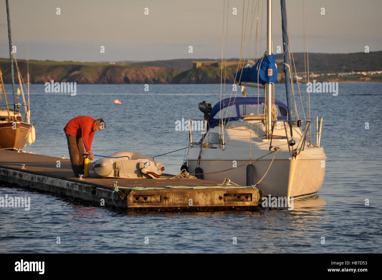 Yachtsman inflating his dinghy at Dale outer pontoon before going ashore Stock Photo