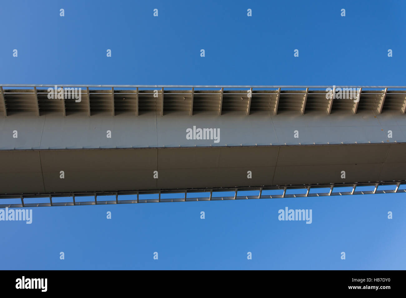 Quirky but interesting shot of the underside of a section of bridge looking angular and modern against a clear blue sky Stock Photo