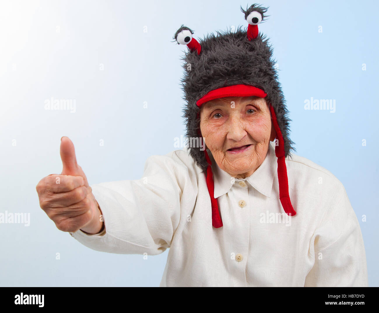 very old lady in funny fur hat with two tentacles showing thumbs up Stock  Photo - Alamy