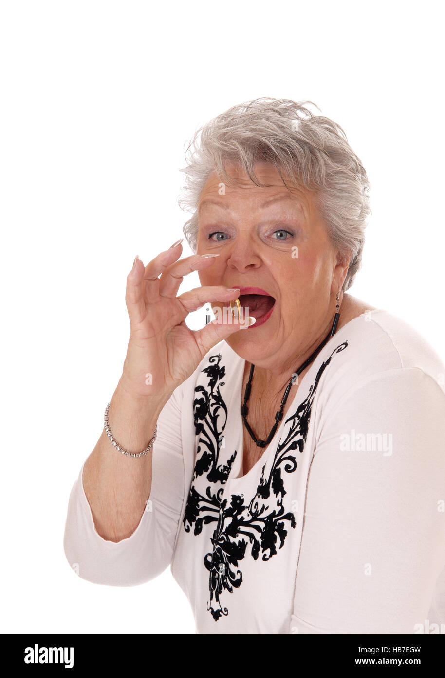 Senior woman swallowing vitamin pill. Stock Photo