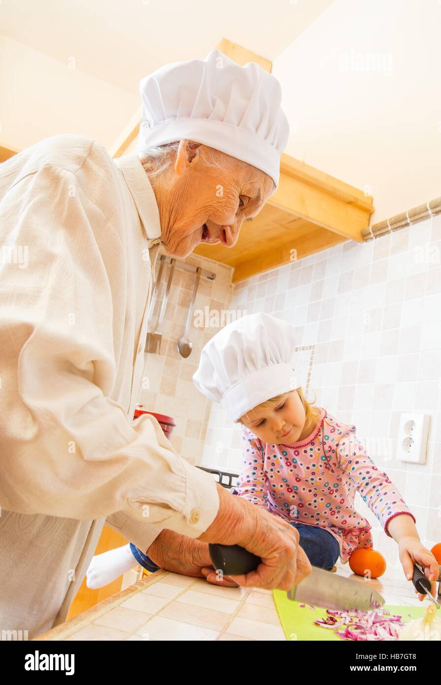 Little girl keeping companion for elderly lady in the kitchen. Stock Photo