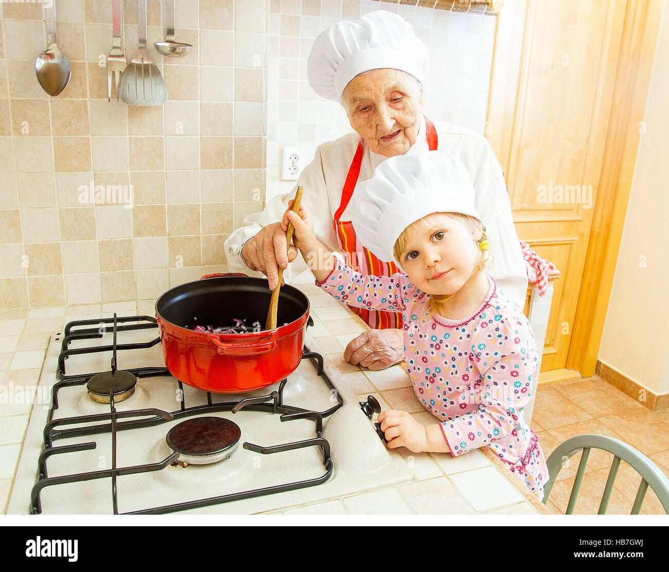 Grandmother cooking together with grand-daughter in the kitchen. Stock Photo