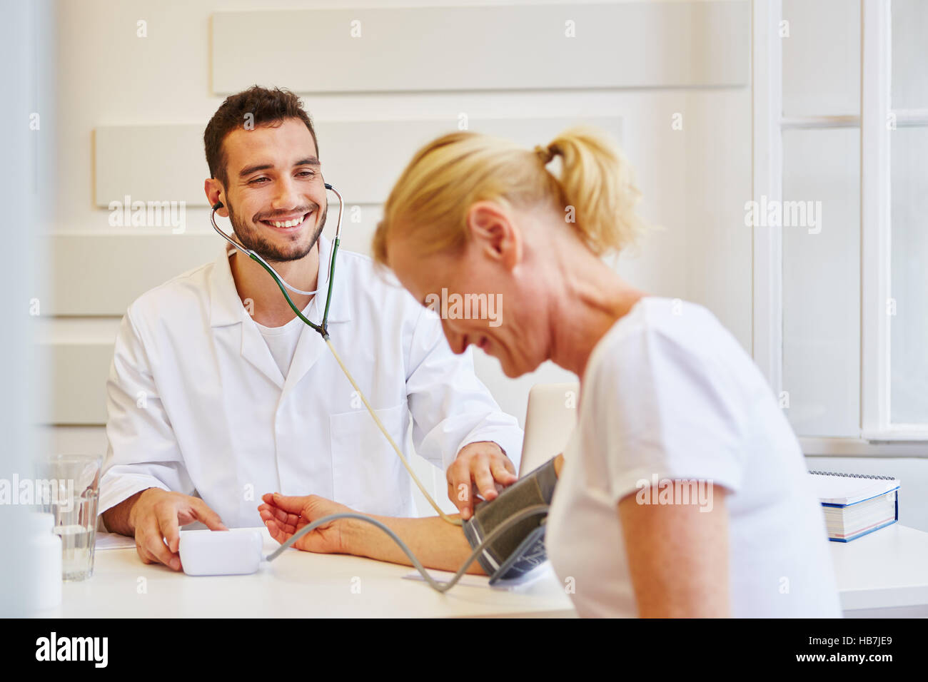 Friendly doctor with patient measures her blood pressure Stock Photo