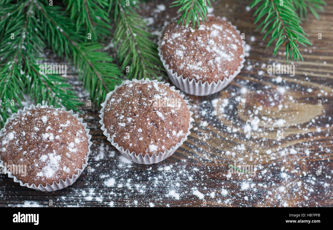 Christmas and New Year winter holiday composition of three cakes on snowbound wooden space background with green fir tree branches Stock Photo