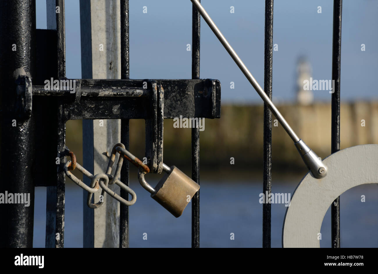 Padlock and chain on gate preventing access with lighthouse in background Stock Photo