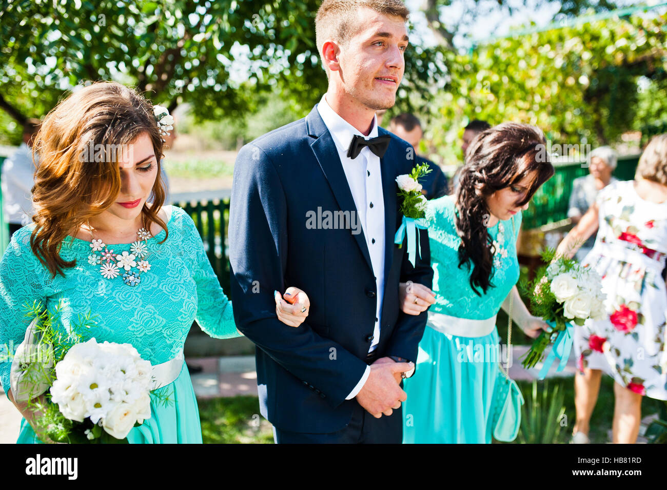 Bridesmaid holding groom under arms Stock Photo