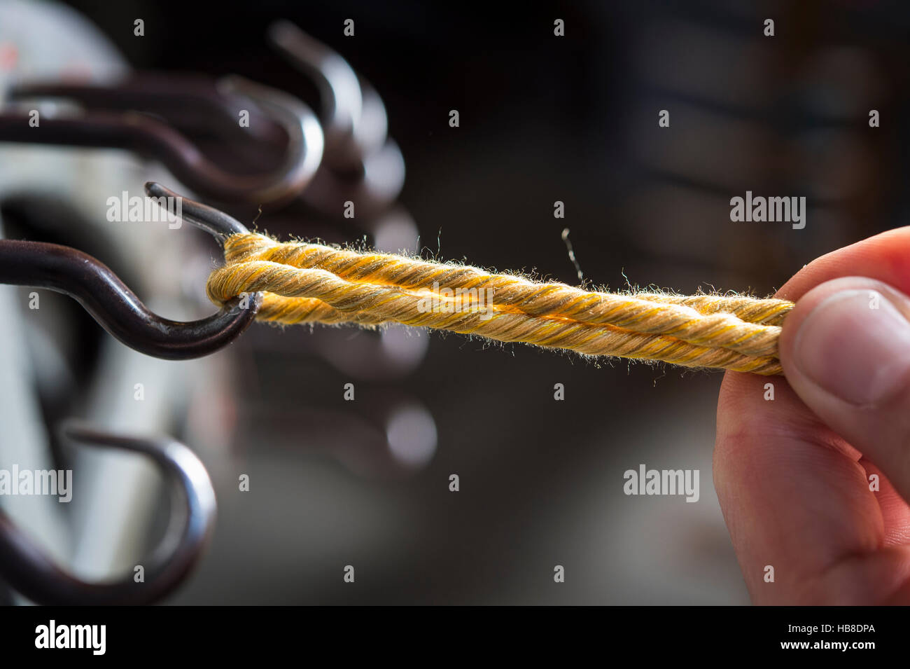 Passementerie maker, hand guiding cord on hook of cord twisting wheel