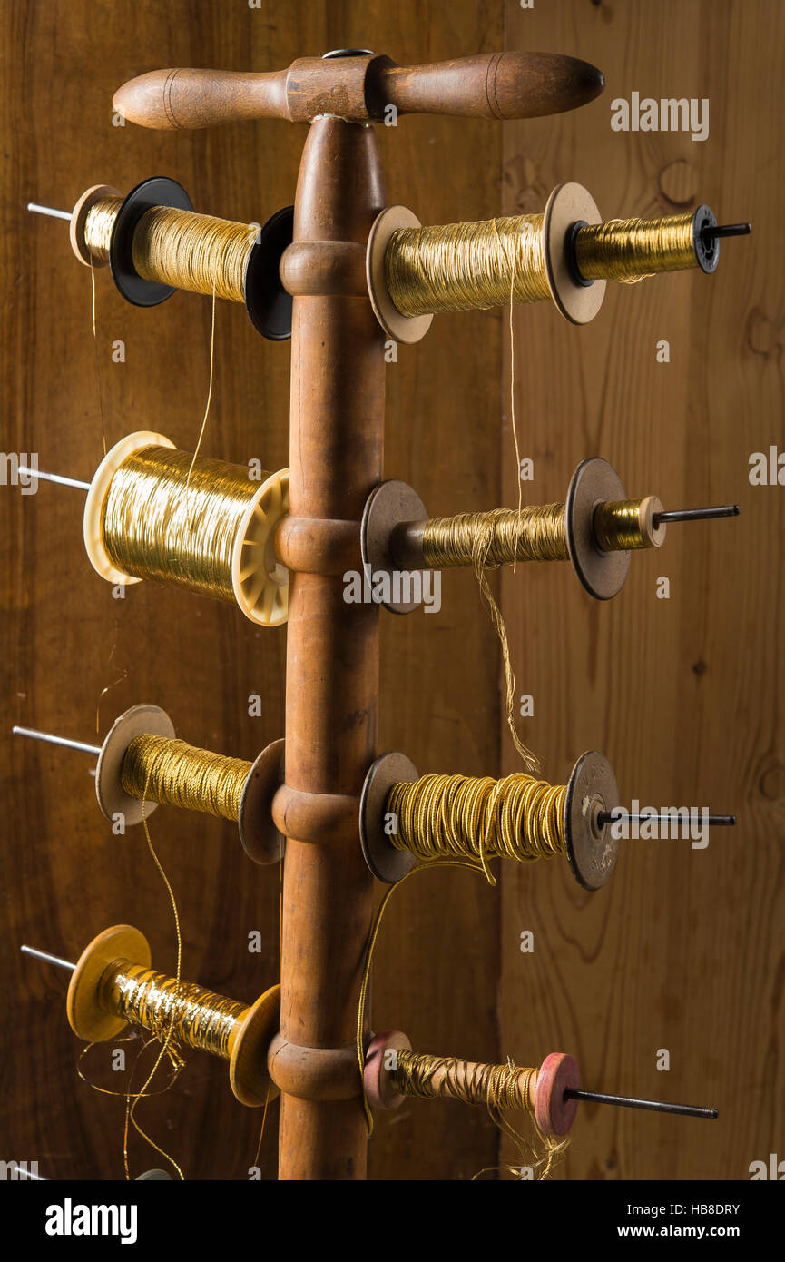 Thread stand in front of wooden wall with various gold and yellow yarns, Munich, Bavaria, Germany Stock Photo